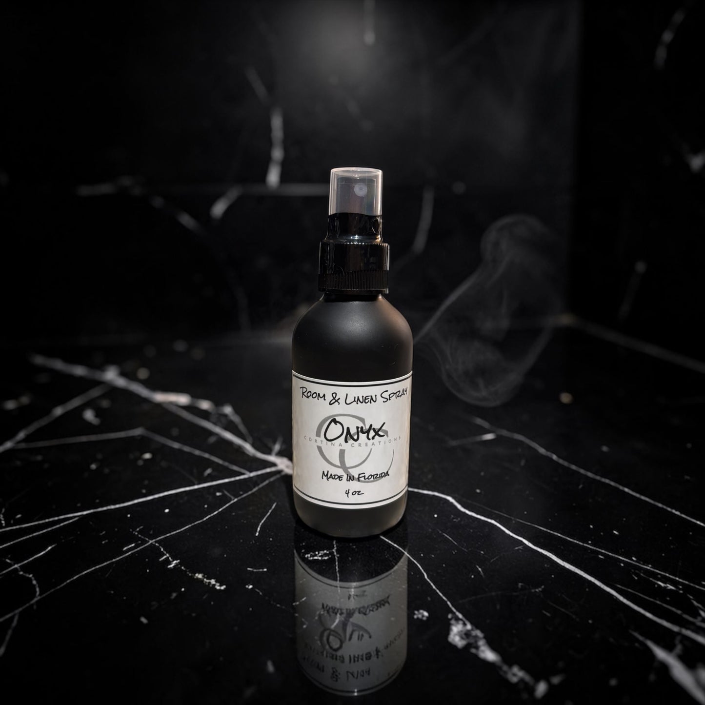 Black spray bottle with a label on a dark surface with smoke effect