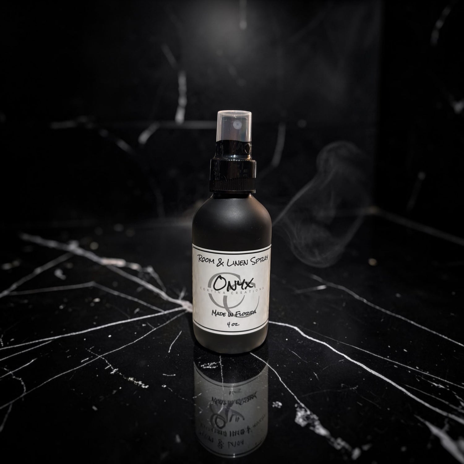 Black spray bottle with a label on a dark surface with smoke effect