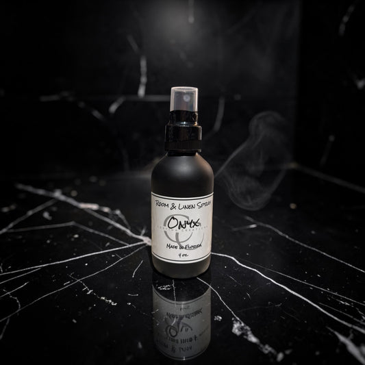 Black spray bottle with a label on a dark surface with smoke effect