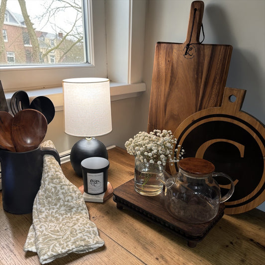 Kitchen counter with wooden cutting boards, a lamp, and kitchen utensils near a window.