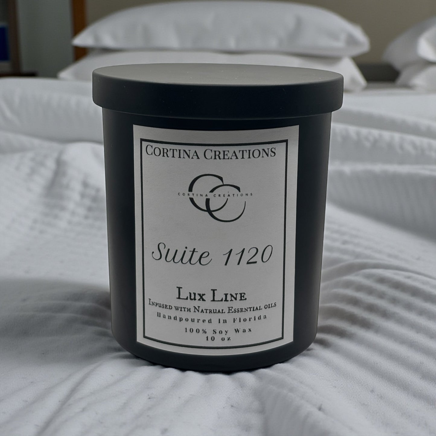 Cortina Creations candle on a bed with white bedding