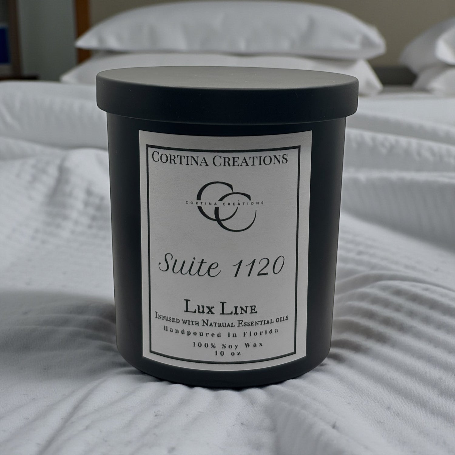 Cortina Creations candle on a bed with white bedding